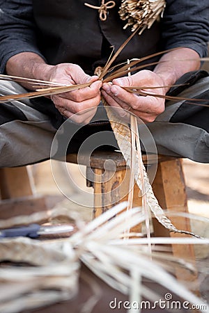 Old wicker craftsman with hands working in isolated foreground Stock Photo