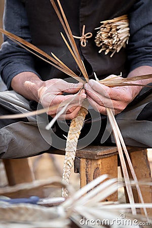Old wicker craftsman with hands working in isolated foreground Stock Photo