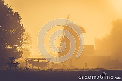 Old windmill at golden sunrise light, misty morning after rain Stock Photo