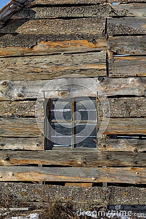 Old window frame in a vintage wooden wall in aold farm house. Old wooden wall with window detail of an old building in ruins. Stock Photo