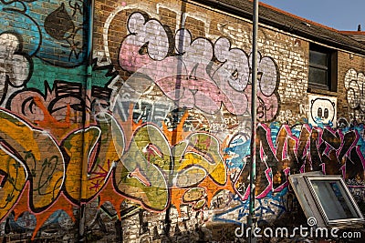 Old window frames leaning on the wall with colorful graffiti. Editorial Stock Photo