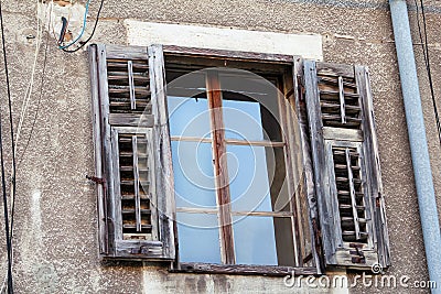 Old window with rotten and cover wooden shutters of historical building in Pula, Croatia, closeup / Building facade elements. Stock Photo
