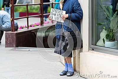 an old woman with cardboard in her hands asks for money on the street. Translation of & x22;Help for the sake of Christ bread Stock Photo