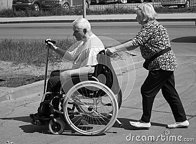 Old woman carries disabled carriage with old man Editorial Stock Photo