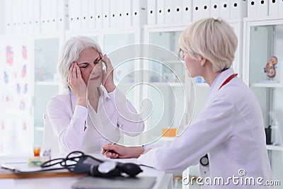 Old woman complains on strong migraine to doctor in hospital Stock Photo