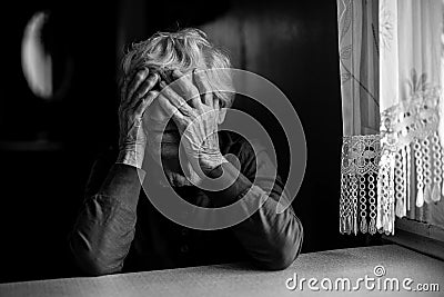 Old woman covers her face with wrinkled hands. Black and white photo. Stock Photo