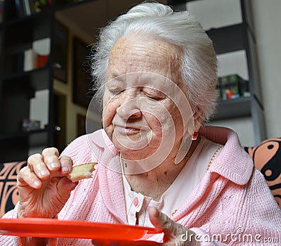 Old woman eating a slice of bread Stock Photo