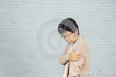 Old woman hurt on the shoulder on gray background Stock Photo