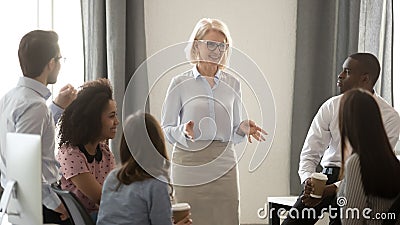 Old woman mentor coach training multicultural interns group in office Stock Photo