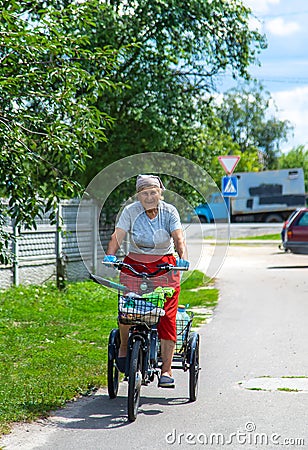 An old woman rides a bicycle. Selection focus. Stock Photo