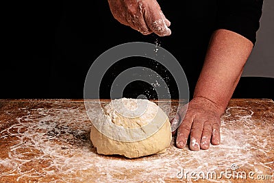 The hands of an old grandmother sprinkle with flour dough Stock Photo