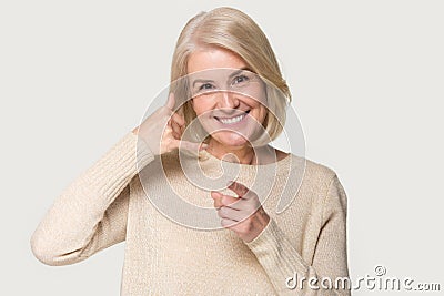 Old woman showing call back sign isolated on grey background Stock Photo
