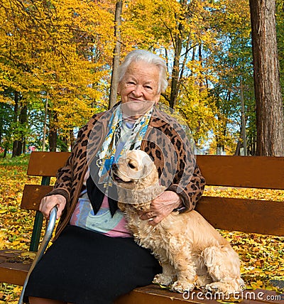 Old woman sitting on a bench with a dog Stock Photo