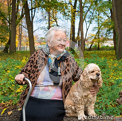 Old woman sitting on a bench with a dog Stock Photo