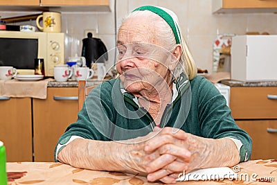 An old woman sitting by the table at the kitchen Stock Photo