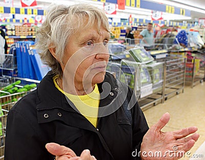 Old woman stands helpless in a supermarket Stock Photo