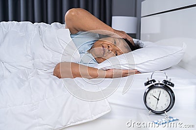 Old woman suffering from insomnia is trying to sleep in bed Stock Photo