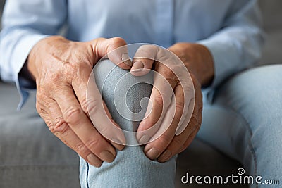 Old woman touching knee feeling pain suffering from osteoarthritis, closeup Stock Photo