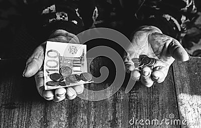 Old woman with very little money. Poverty concept. Pensioner with one euro note and coins in hands. Economy and crisis in the Stock Photo