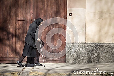 Old woman wearing a erbiantraditional back outfit walking alone in the streets of Sombor. Editorial Stock Photo
