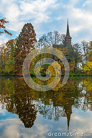 Old wood church reflected in the pond. Tree mirrored in the water on the left Stock Photo