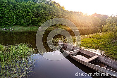 Old wooden boat shore of river surrounded by forest at sunny sum Stock Photo