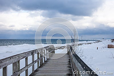 An old, wooden bridge crosses a section of frozen Georgian Bay waterfront in Collingwood Stock Photo