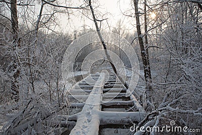 Old wooden broken footbridge covered with snow Stock Photo