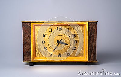 Old wooden clock with with dial in yellow frame and black hands and numbers. Brown vintage watch from USSR with wooden Stock Photo