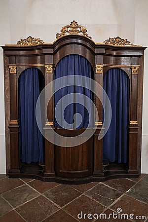 Old wooden confessional with carvings and heavy blue curtains. Stock Photo
