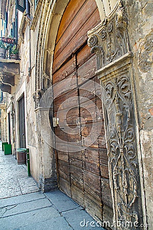 Old wooden door with a brick wall on a narrow street. Side view. Stock Photo