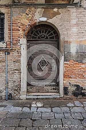 An old wooden door and wall weathered by age in Venice, Italy Stock Photo