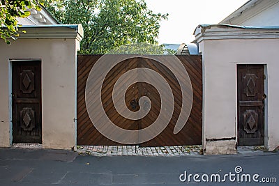 Old wooden entrance gate with iron handles. On each side - two additional small input wooden gates. The architecture of the 18th c Stock Photo