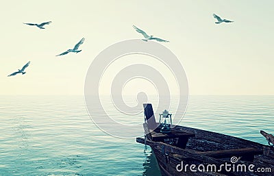 Old wooden fishing boat floating over calm blue sea and sky Stock Photo