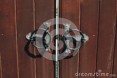 Old wooden gates with forged vintage round handles closeup Stock Photo