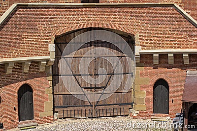 Old wooden gates on metal forged canopies in a red brick building. Editorial Stock Photo