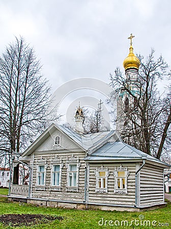 Old wooden house on a green meadow with carved windows. Church in the background. Russian old house. izba ancient Stock Photo