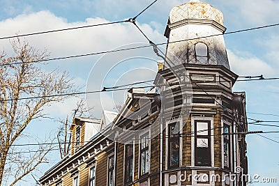 An old wooden house similar to a church, next to which the tram line wires pass. View from below against the blue sky Stock Photo