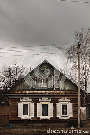 Old wooden house with white shutters in cloudy weather Stock Photo