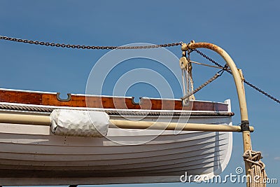 Old wooden lifeboat hoisted up on the side of an old tall ship, rigging details Stock Photo