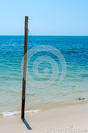 Old Wooden post stuck in white sandy beach. Stock Photo