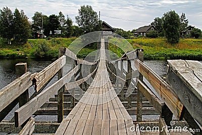 Old wooden suspension bridge over the river in village Stock Photo