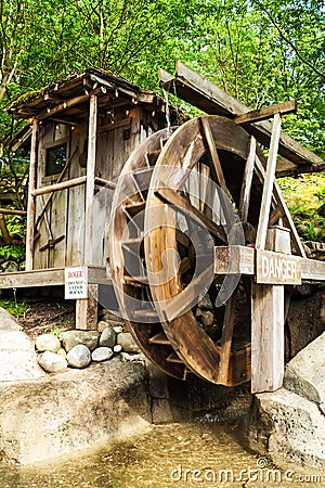 Old wooden water mill with the wheel turning Stock Photo