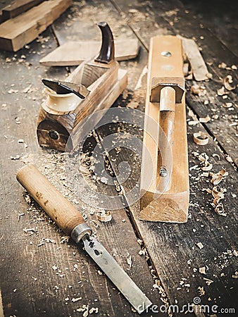 Old woodworking hand tool: wooden plane, chisel and in a carpentry workshop on dirty rustic table covered with sawdust Stock Photo