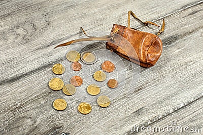 Old worn brown leather coin pouch, with euro coins spilled on g Stock Photo