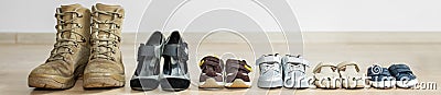 Old worn military boots, women`s shoes and lot of baby shoes on wooden floor. Banner for web site Stock Photo