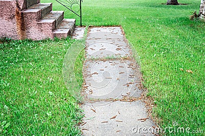 Old worn out cement side walk surrounded by grass Stock Photo