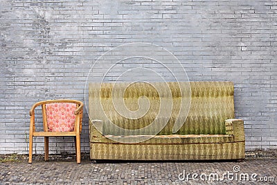 Worn-out furniture against a gray brick wall, Beijing, China Stock Photo