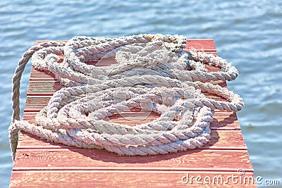 Old worn-out mooring rope rolled into a bay lies on a wood Stock Photo