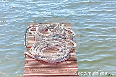 Old worn-out mooring rope rolled into a bay lies on a wood Stock Photo